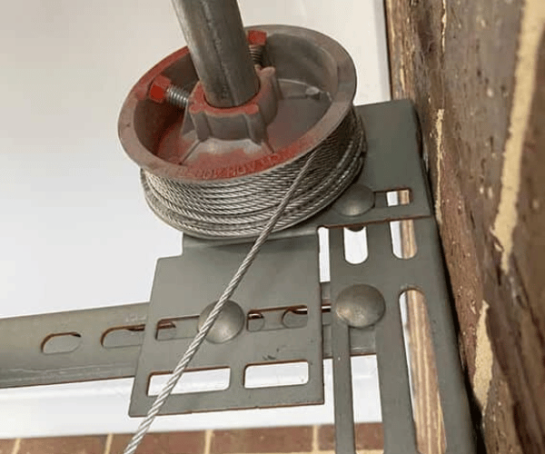 Technician rewinding garage door cable onto drum in San Francisco Bay Area residential garage