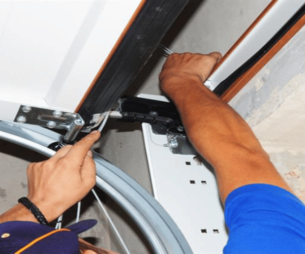 Technician installing new weather seal on garage door bottom in San Francisco Bay Area home