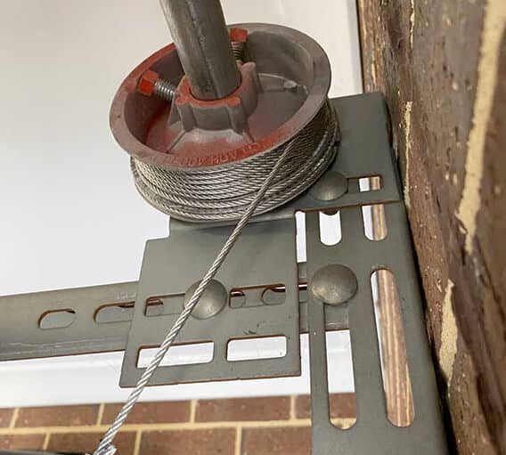 Professional technician inspecting garage door springs and cables during maintenance service in San Francisco Bay Area