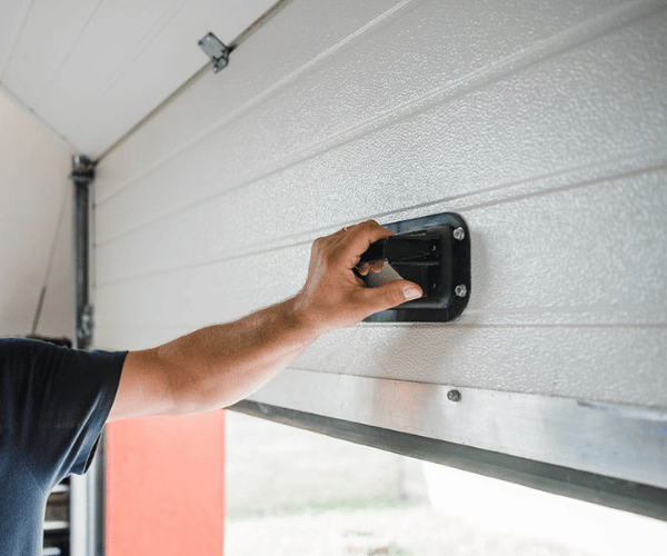 Professional technician repairing broken garage door lock mechanism in San Francisco Bay Area home